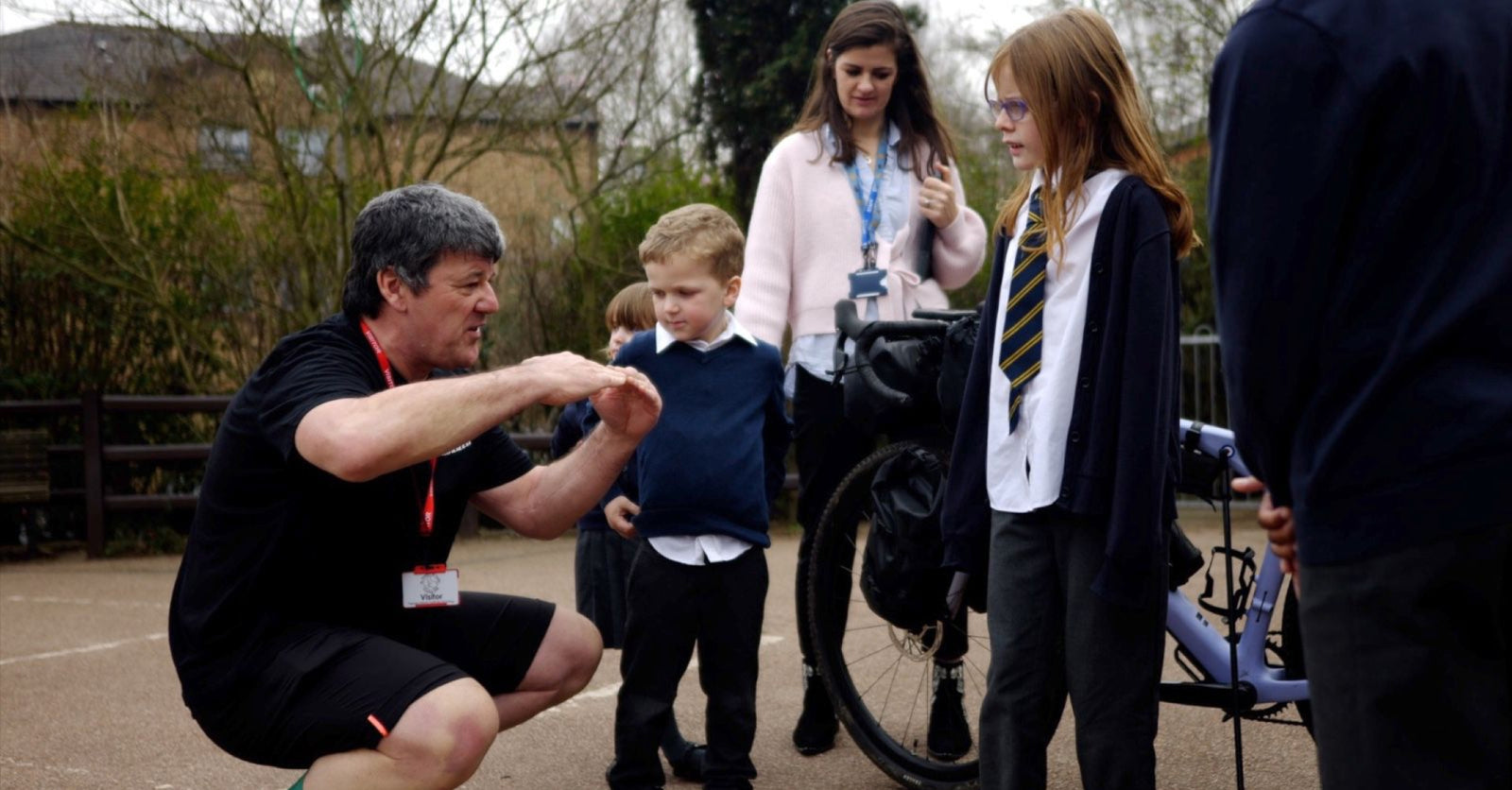 Stephan crouched, talking to several school children