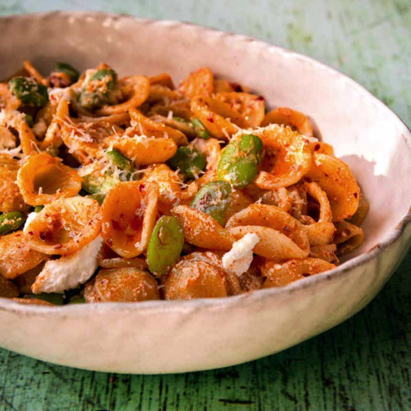 Circular pasta shape dish with green beans in a white bowl
