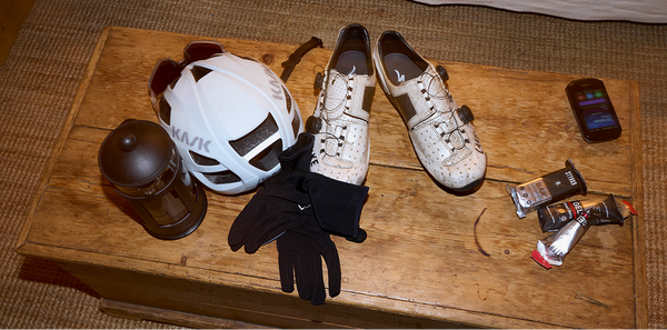Cyclist essentials: Helmet, shoes and gels on a table.