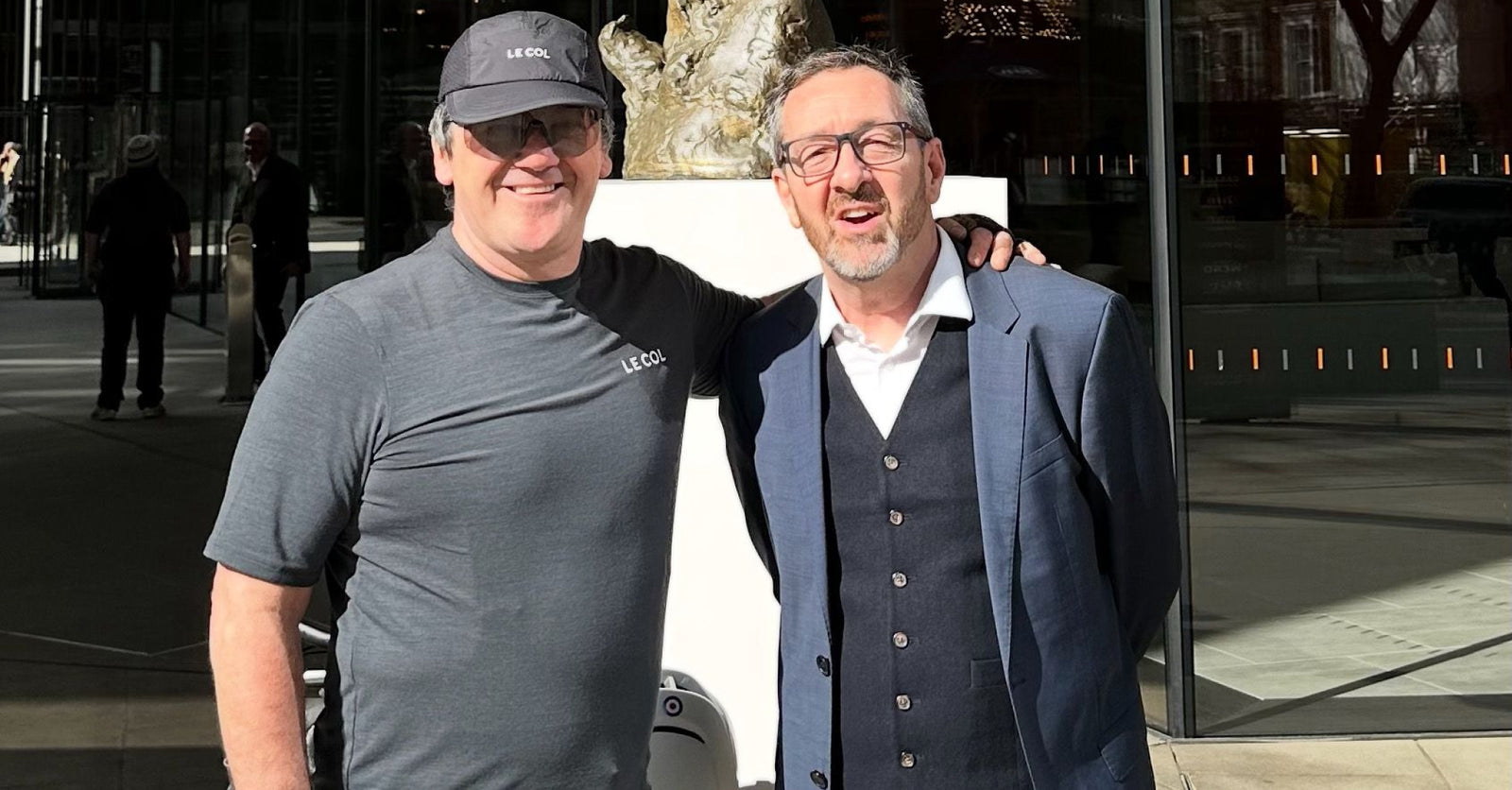 Stephan in Le col t-shirt and cap posing with a business man