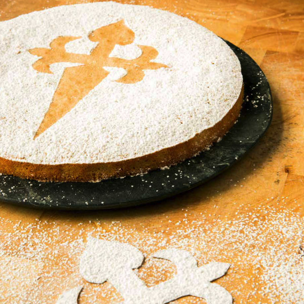 Circular cake covered in icing sugar with decorative shape blocked out