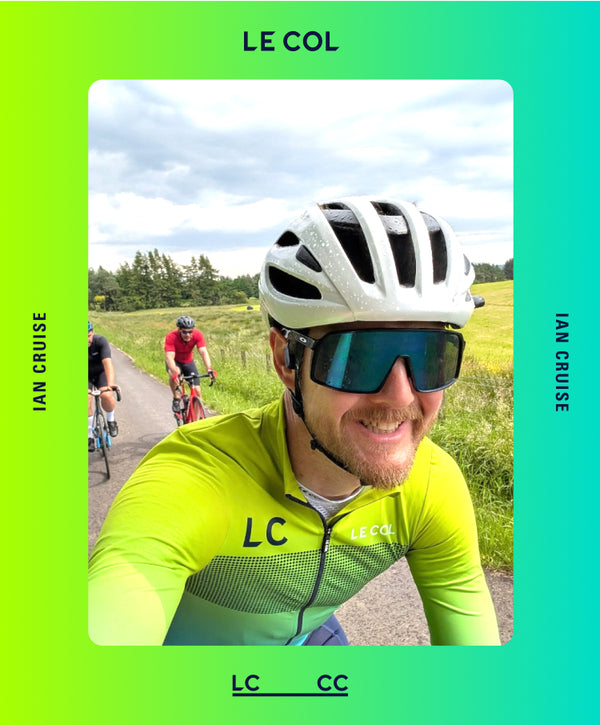 Cyclist in a LCCC fade jersey on a road with other cyclists in the background.