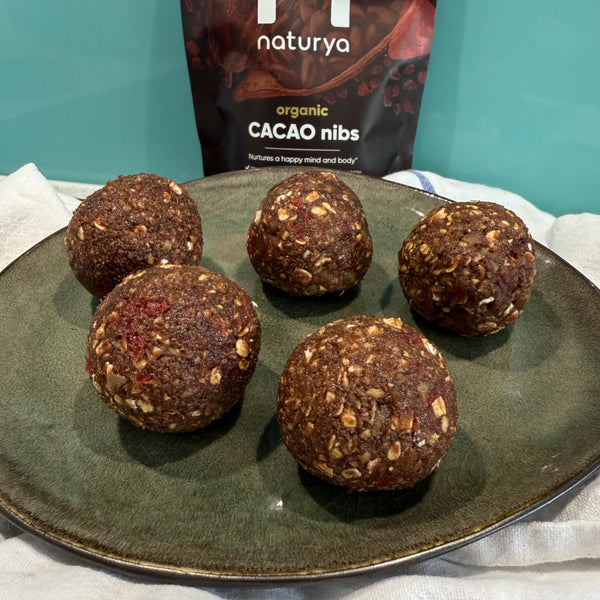 Five brown balls of oats and cocoa on a grey plate