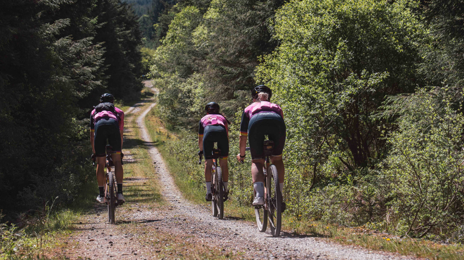 Three Ribble cyclists on a gravel path surrounded by trees