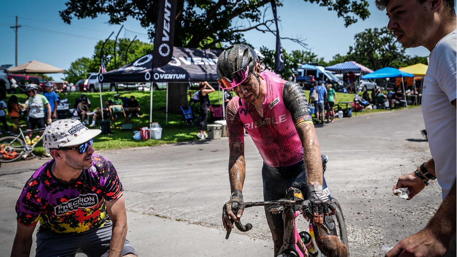 Ribble cyclist with mud on their face approaches an event setup