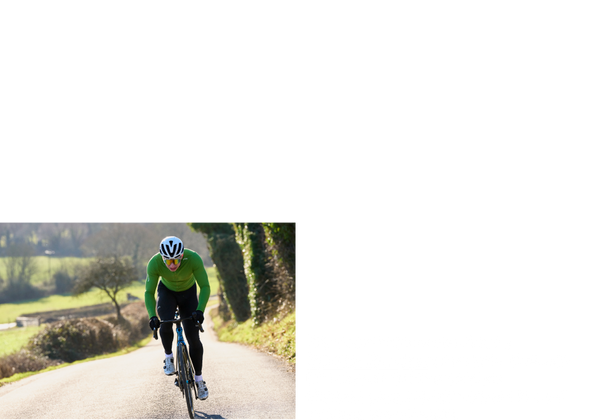 Male cyclist almost at the summit of a hill on a countryside road.