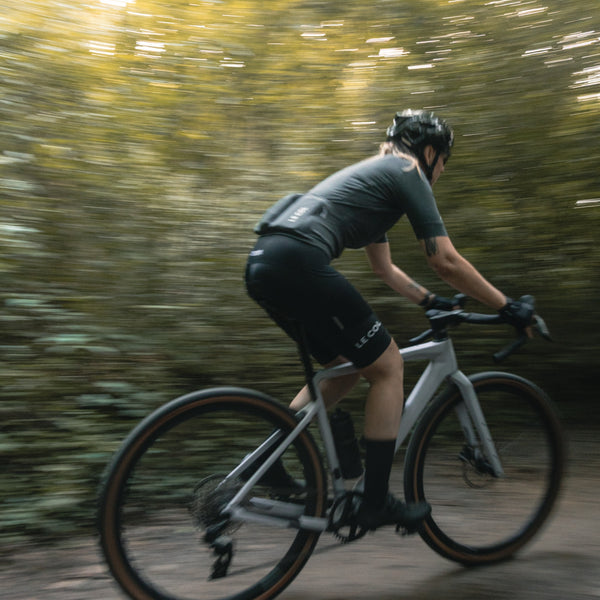 Blurred shot of Alexandra cycling away on a forested track.