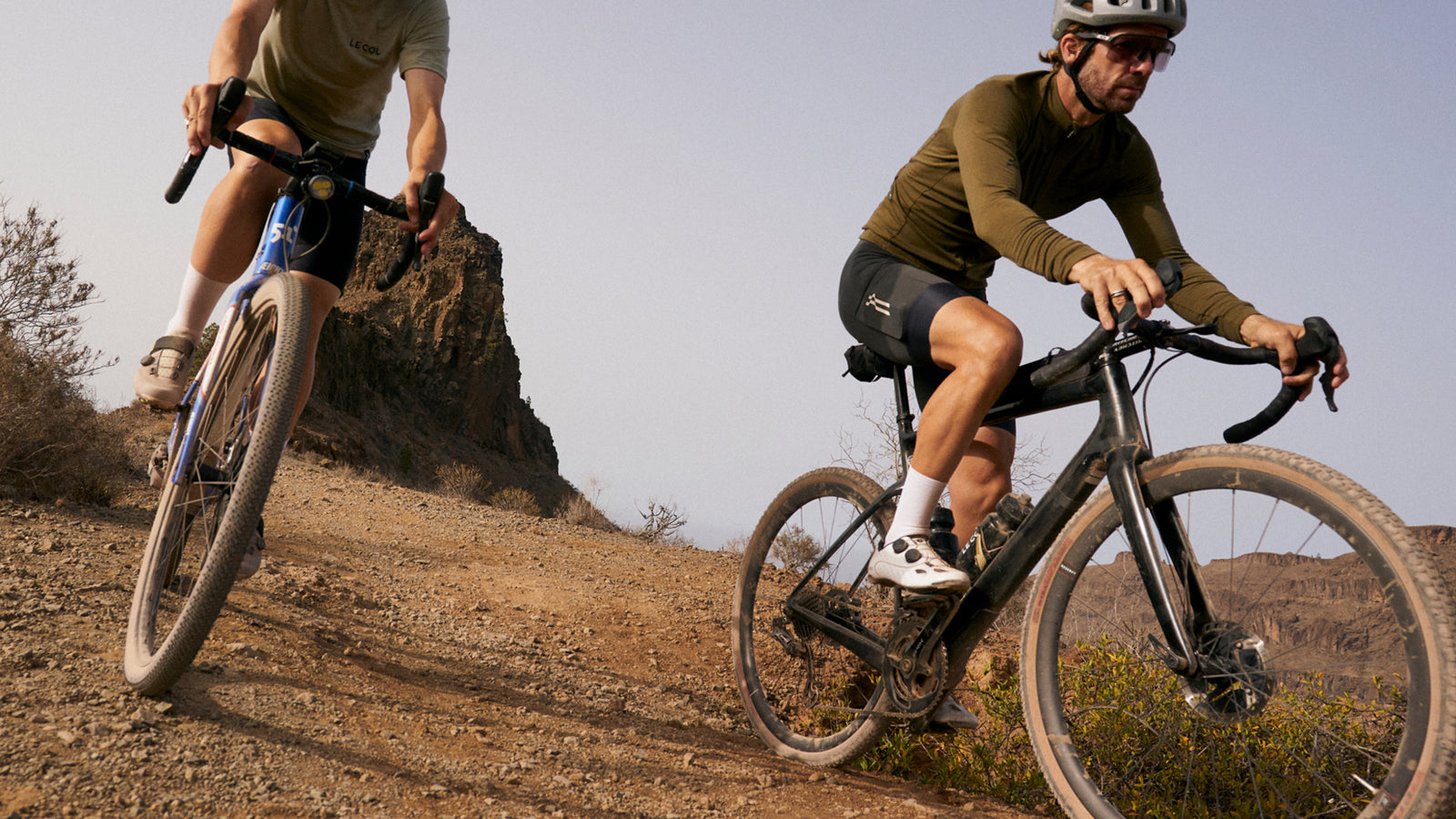 upward shot of two male riders coming downhill on gravel track.