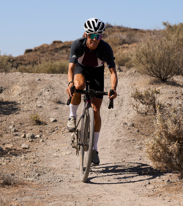 Female rider coming towards down a gravel track in short sleeve grey jresey.
