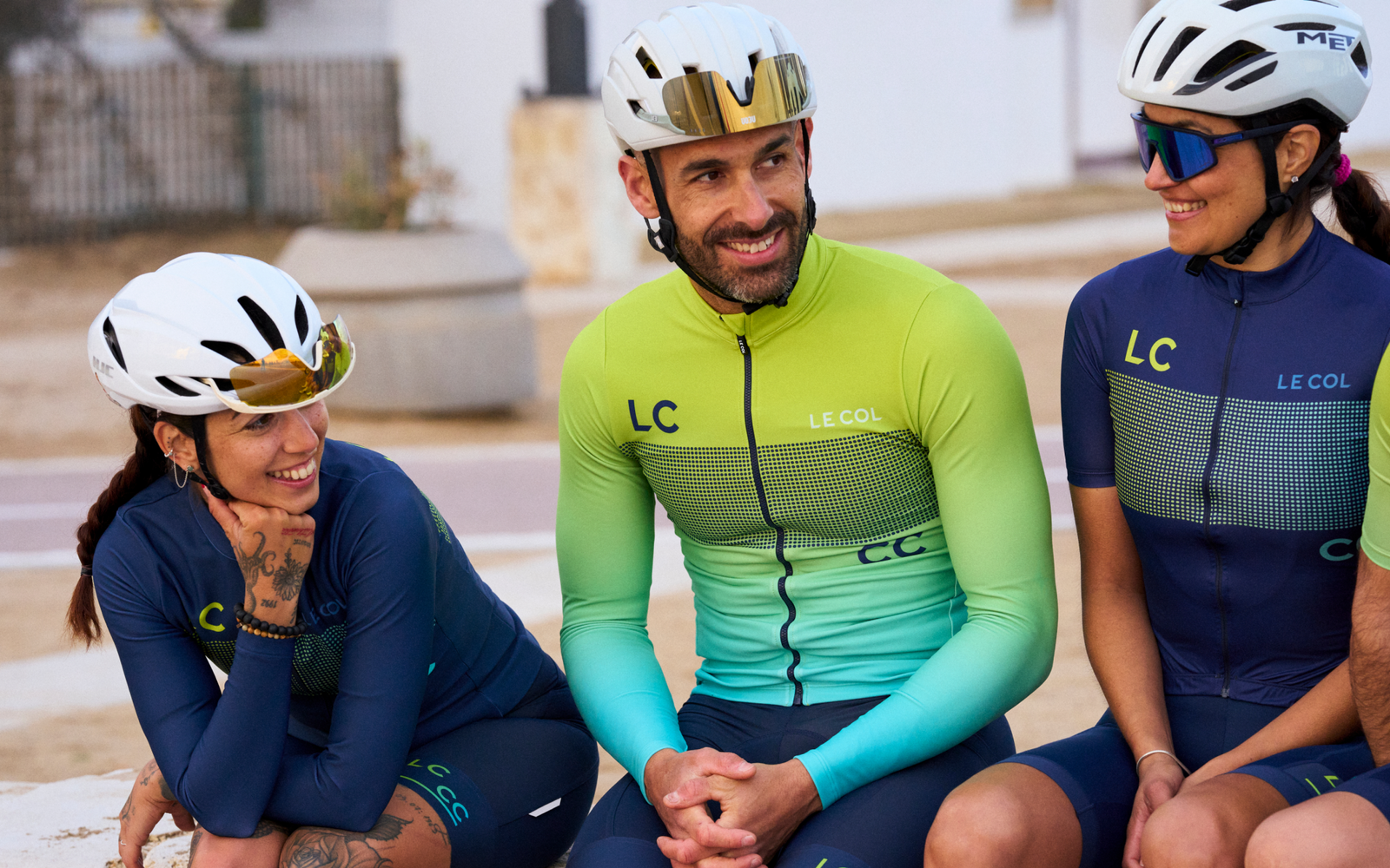 Three cyclists sat on a wall in long sleeve LC_CC jerseys