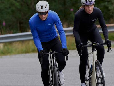 male and female cyclists riding towards the frame in blue and black jerseys