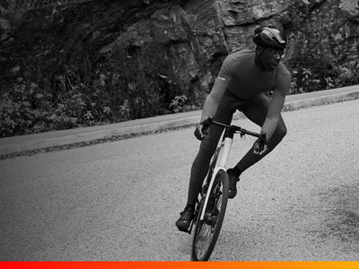 Cyclist riding on a road with rocky cliffs in the background