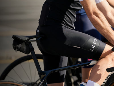 Cyclist in black LE COL outfit riding a bicycle with a blurred background