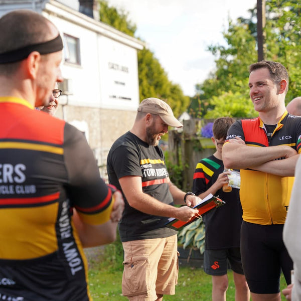 Several men stood chatting, wearing 'Towy Riders' Le Col Kit.