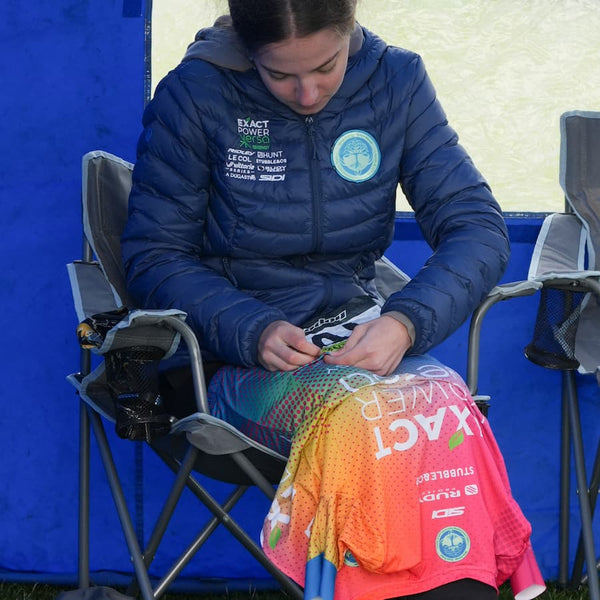 Girl pinning a racing number onto a cycling jersey.
