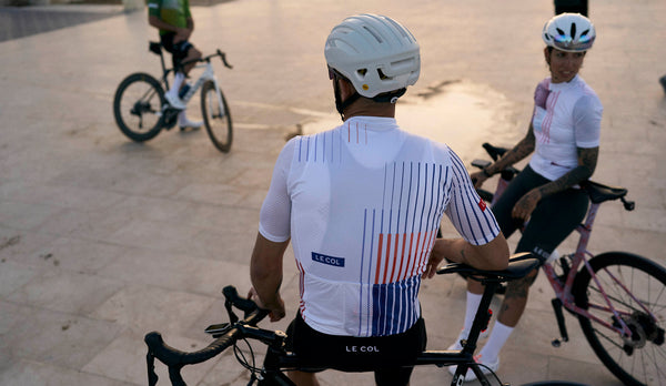 Back of male cyclist in white jersey with blue and orange stripes.