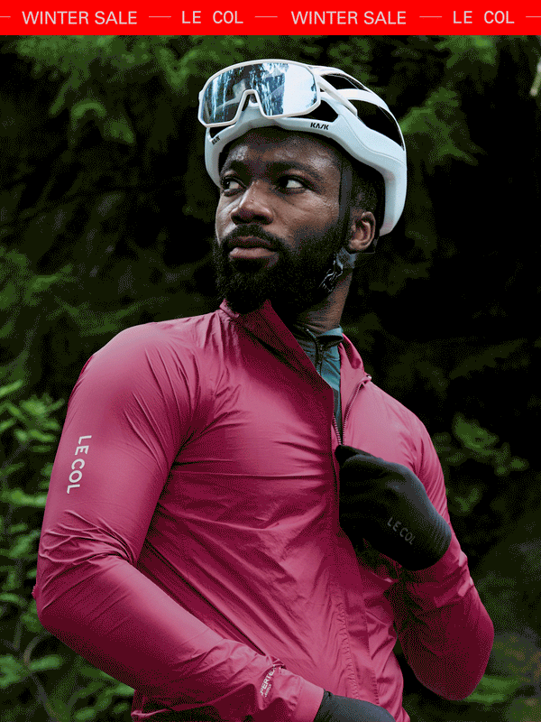 Male cyclist unzipping a pink lightweight rain jacket