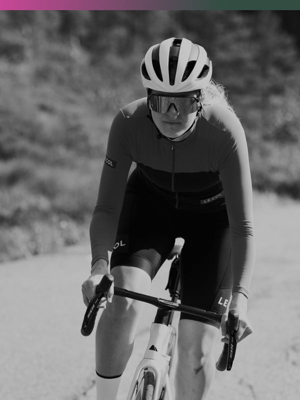 Black and white shot of female cyclist in long sleeve jersey and bib shorts.