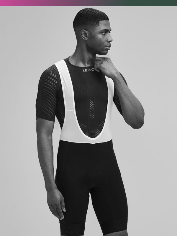 Black and white studio shot of male in mesh base layer and bib shorts.