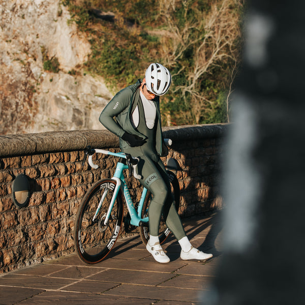 James in full green Le Col Kit resting on his bike on the clifton bridge, bristol.