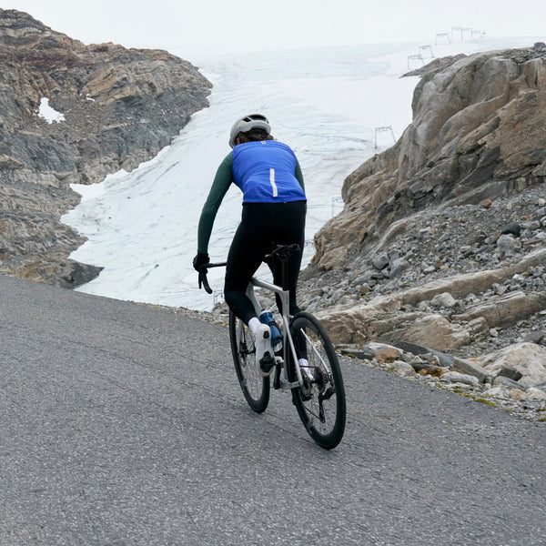 Christian cycling in long sleeve jersey and gilet with rocky landscape and iced over river behind.