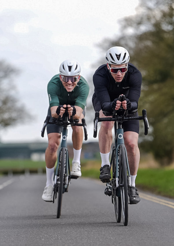 Colin and Lucas leant forward in race positions riding towards.