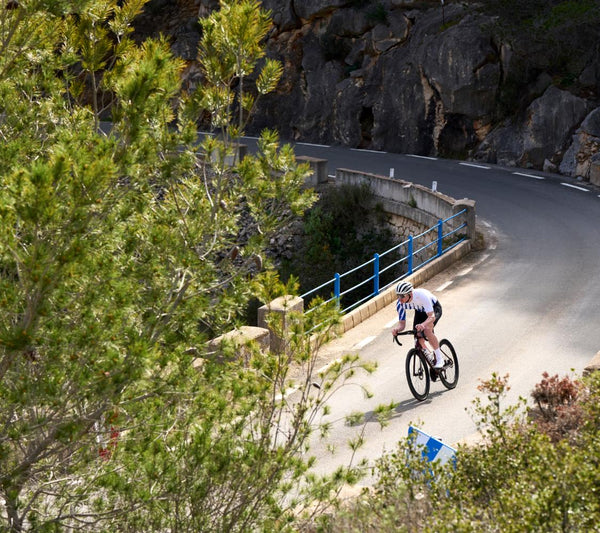 Cyclist on a mountain road with rocky cliffs and greenery