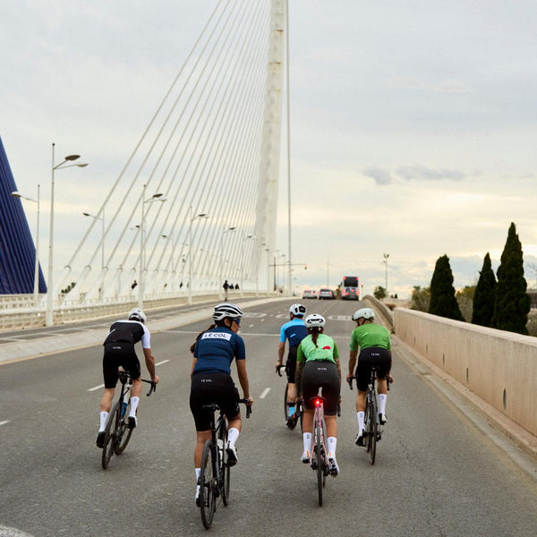 Group of cyclists riding on a bridge during sunset.