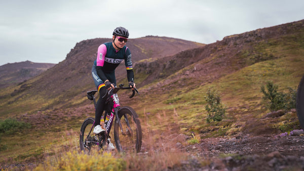 Male cyclist going uphill with large rocky hills in the background. 