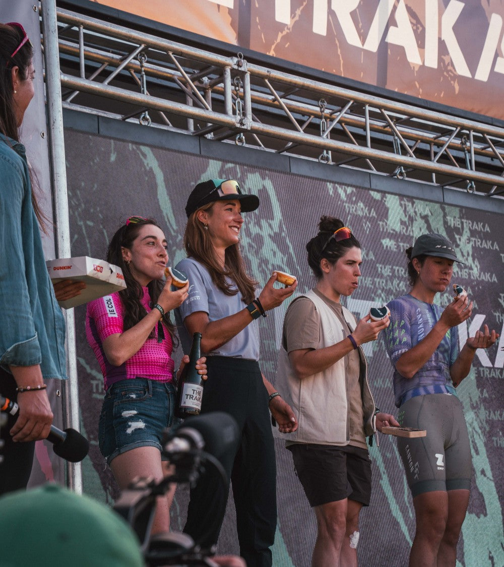 four women on a stage eating doughnuts at Traka
