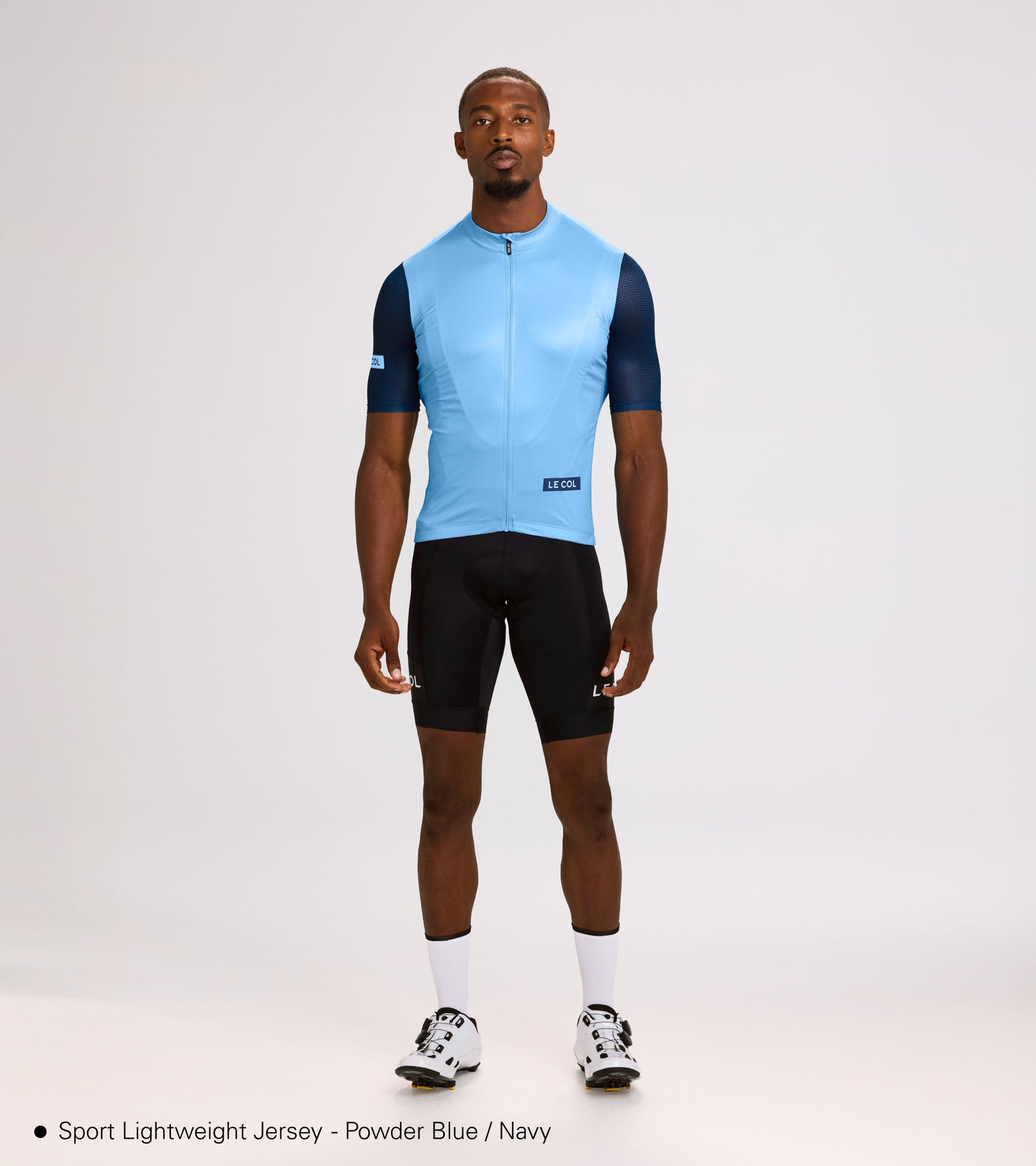 Studio shot of man wearing the light blue lightweight jersey with navy sleeves.