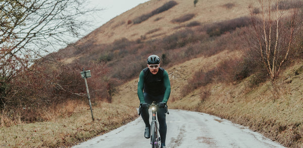 Chris cycling towards in Le Col Kit with moorland hill behind.