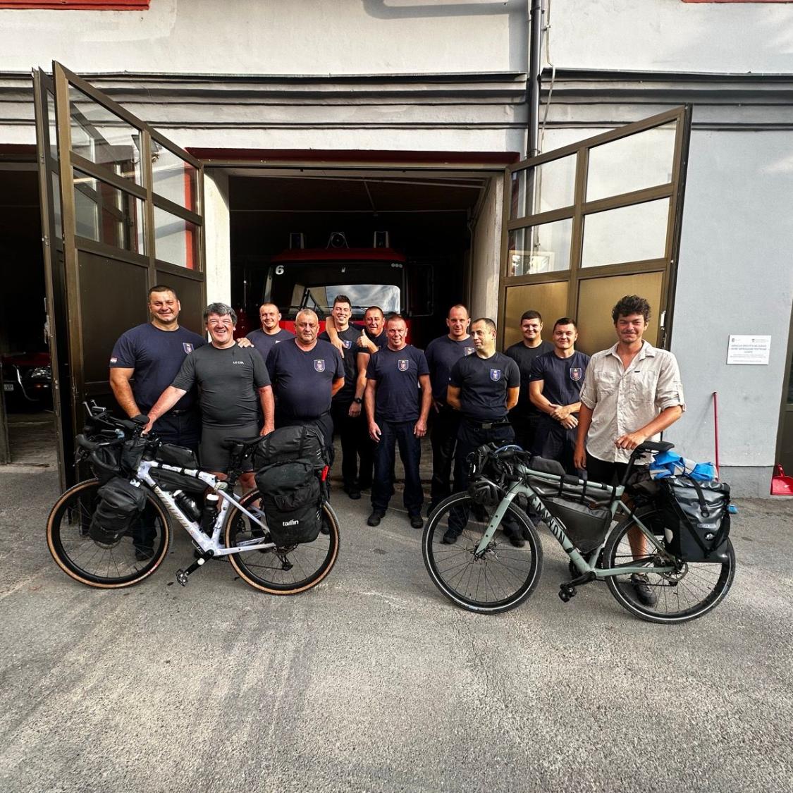 Group of firefighters with bicycles in front of a fire station building